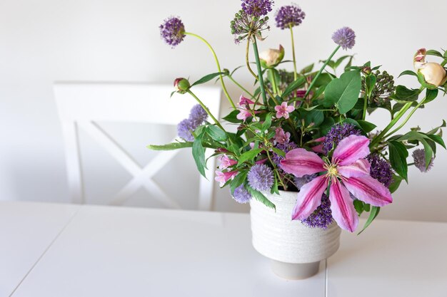 Vase with flowers from the garden in a white kitchen interior