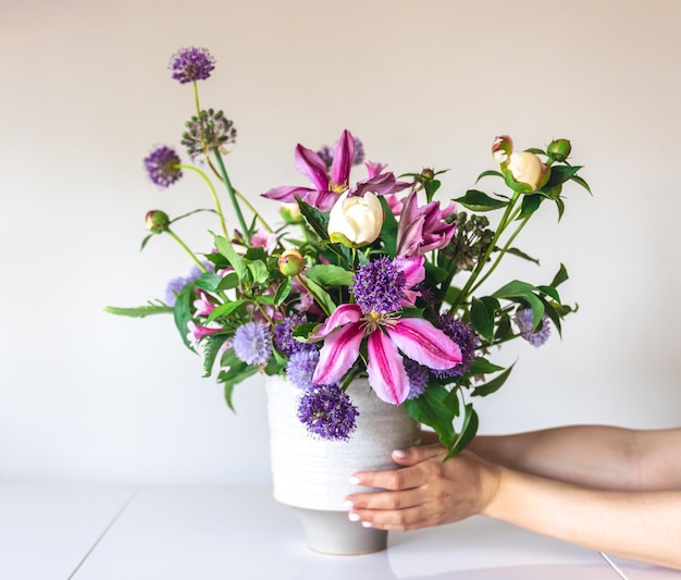 Free photo vase with fresh summer flowers in female hands on a white background