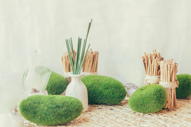 Vase with green sticks and mossed stones