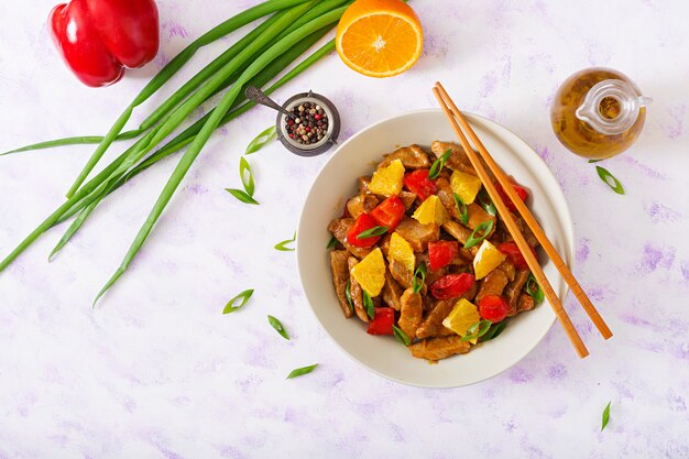 Veal fillet - stir fry with oranges and paprika in sweet and sour sauce on a light table. Flat lay. Top view