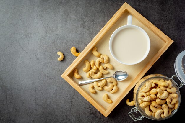 Vegan cashew milk in glass with cashews nuts on dark background