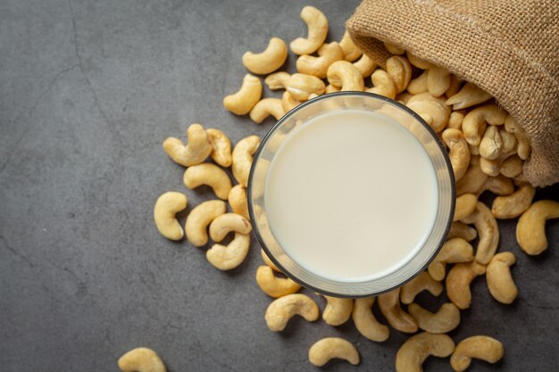 Vegan cashew milk in glass with cashews nuts on dark background