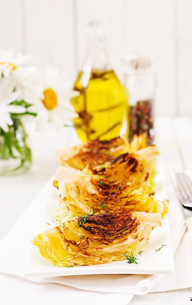 Vegan grilled cabbage steaks on white wooden table. Healthy food.