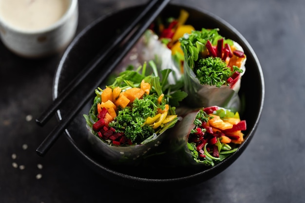 Веганские рулетики из рисовой бумаги с овощами и кунжутом подаются на тарелке, готовые к употреблению