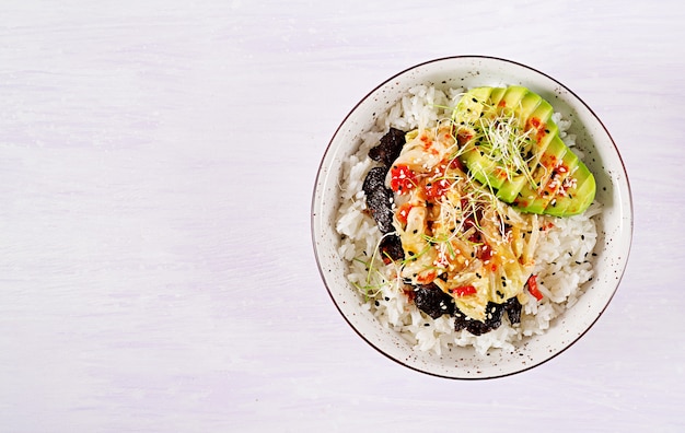 Vegan salad with rice, pickled kimchi cabbage, avocado, nori and sesame on bowl. 