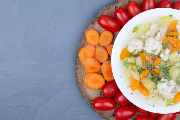 Vegetable broth soup in a white bowl with chopped foods