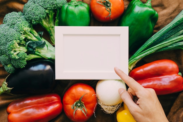 Vegetable composition with finger pointing towards frame