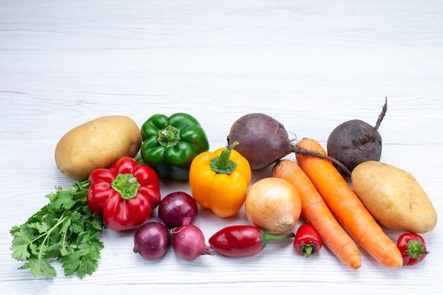 Free photo vegetable composition with fresh vegetables greens carrots onions and potatoes on white desk