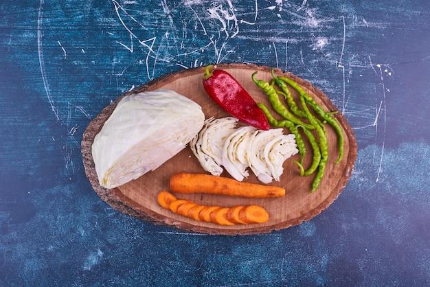 Vegetable mix on a wooden platter on blue space in the middle. 