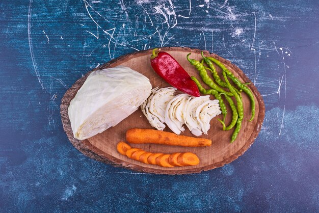 Vegetable mix on a wooden platter on blue space in the middle. 