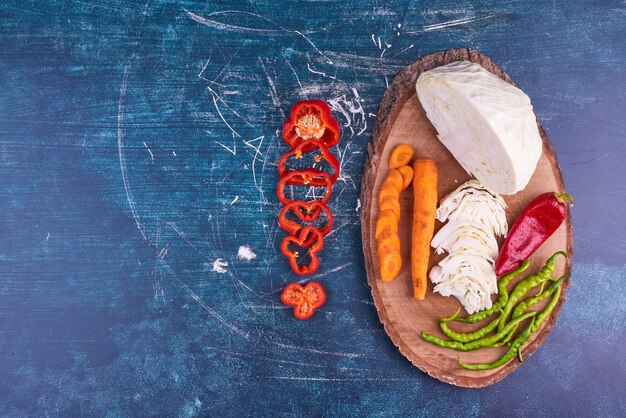 Vegetable mix on a wooden platter on blue space. 