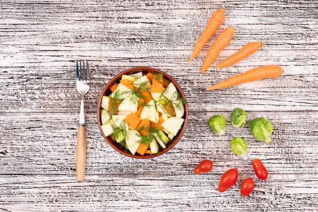 Vegetable salad in a ceramic bowl with fork carrot radish cherry tomato cabbage