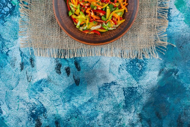 파란색 배경에 삼 베에 접시에 야채 샐러드.