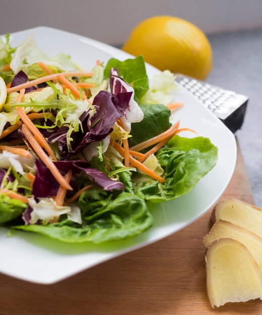 Vegetable salad on plate with lemon on table