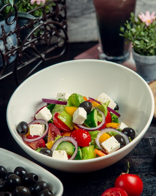 Vegetable salad topped with olives and cheese