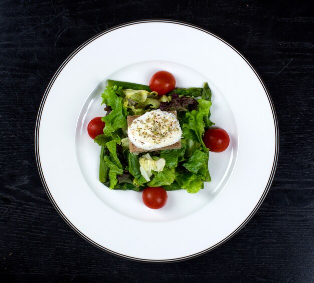 Vegetable salad topped with tomato and cream