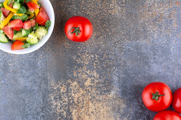 Vegetable salad in a white plate with red tomatoes around