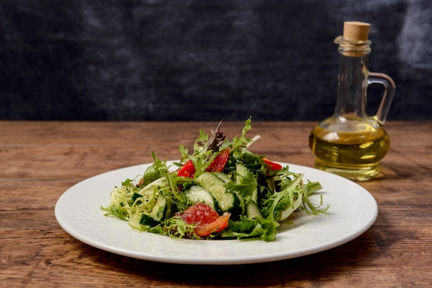 Vegetable salad in white round plate on wooden table.