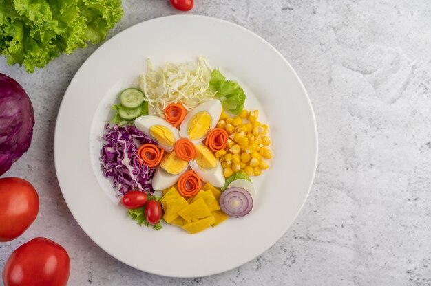 Vegetable salad with boiled eggs in a white dish.