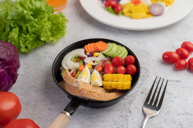 Vegetable salad with bread and boiled eggs in the pan.