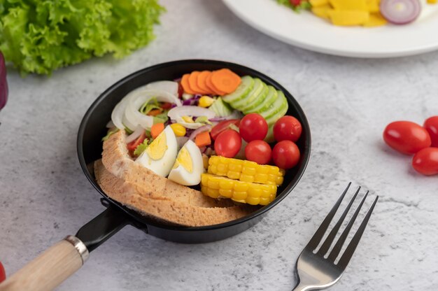 Vegetable salad with bread and boiled eggs in the pan.