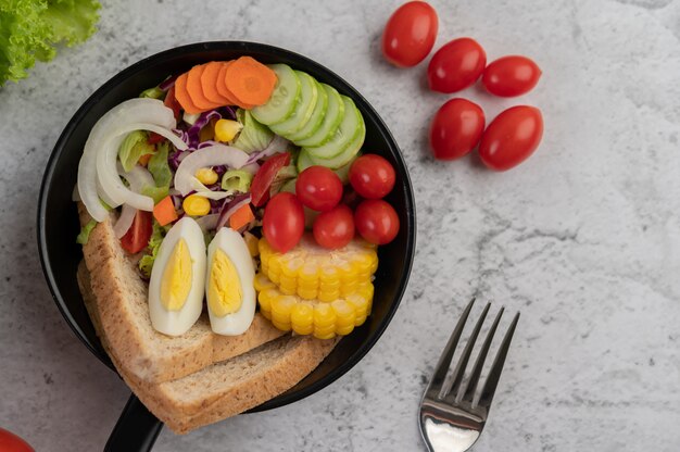 Vegetable salad with bread and boiled eggs in the pan.