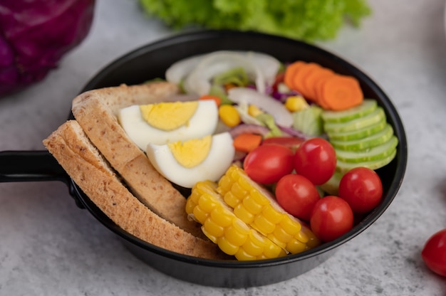 Vegetable salad with bread and boiled eggs in the pan.