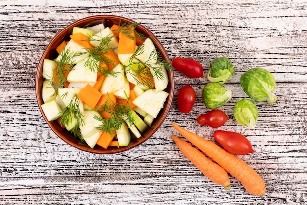 Insalata di verdure con carota e ravanello in una ciotola di ceramica sul tavolo di legno bianco