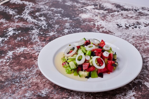 Vegetable salad with chopped and minced ingredients in a white plate, angle view.