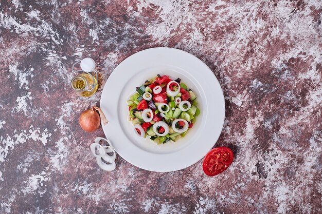 Vegetable salad with chopped and minced ingredients in a white plate, top view