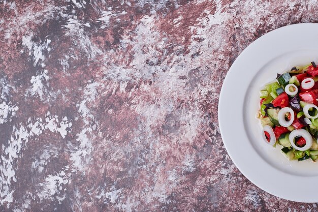 Vegetable salad with chopped and minced ingredients on a white plate, top view.