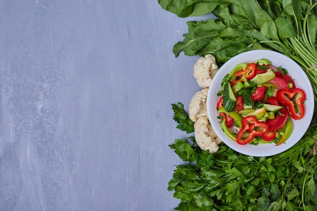 Vegetable salad with herbs on blue