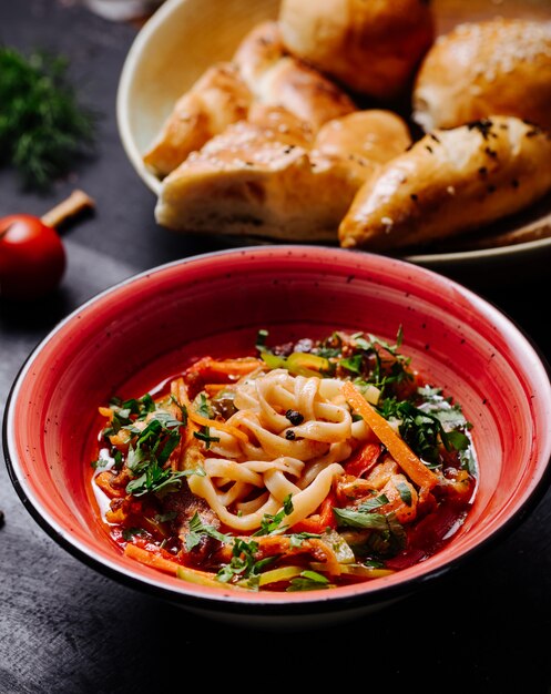 Vegetable salad with herbs in red bowl.