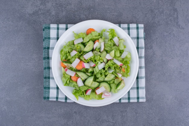 Бесплатное фото Овощной салат со смешанными ингредиентами на клетчатом кухонном полотенце