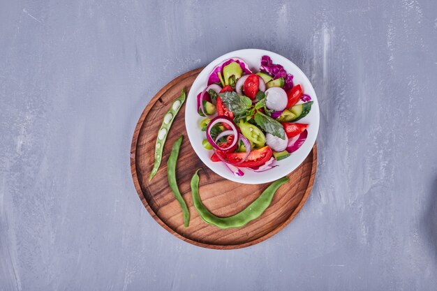 나무 트레이 안에 흰색 접시에 얇게 썬 음식과 다진 음식과 야채 샐러드.