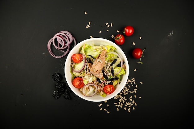 Vegetable salad with tuna and side onion slices top view