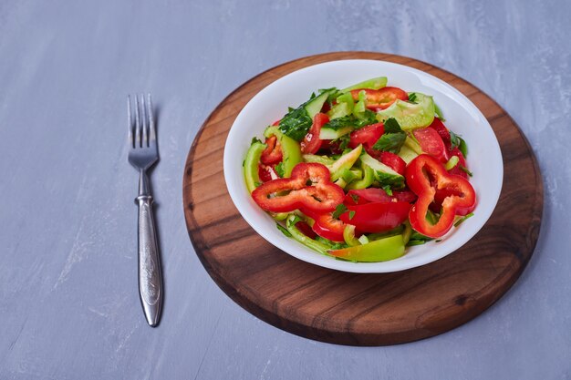 Vegetable salad on wooden board on blue
