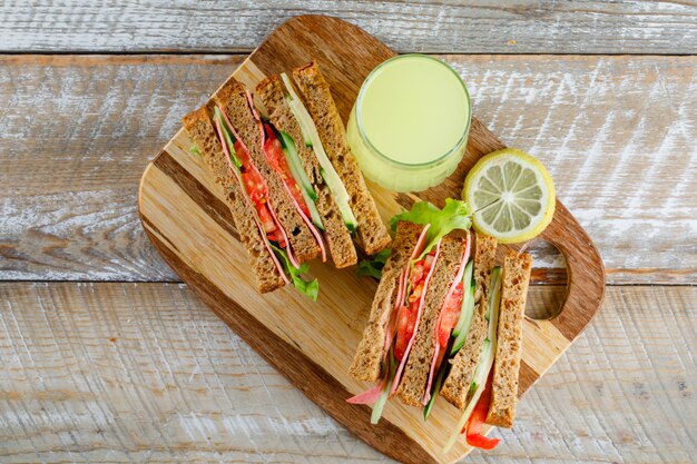 Vegetable sandwich with cheese, ham, lemonade flat lay on wooden and cutting board