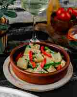 Foto gratuita spezzatino di verdure all'interno del piatto di ceramica con bicchiere di vino bianco.