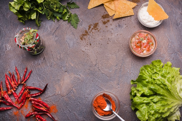 Vegetables among nachos with sauce and chili