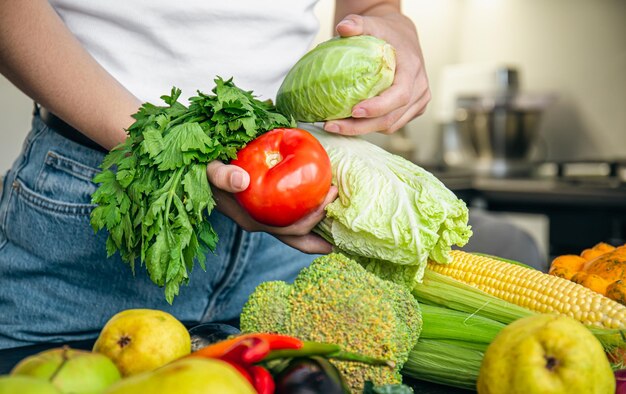 女性の手の中の野菜は、キッチンでの食品の準備の概念を手します。