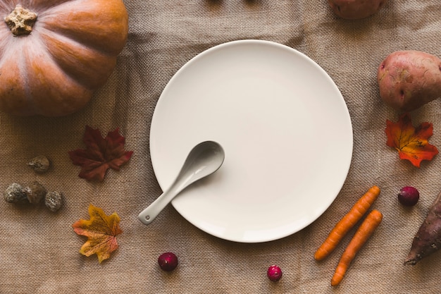 Vegetables and leaves around plate and spoon