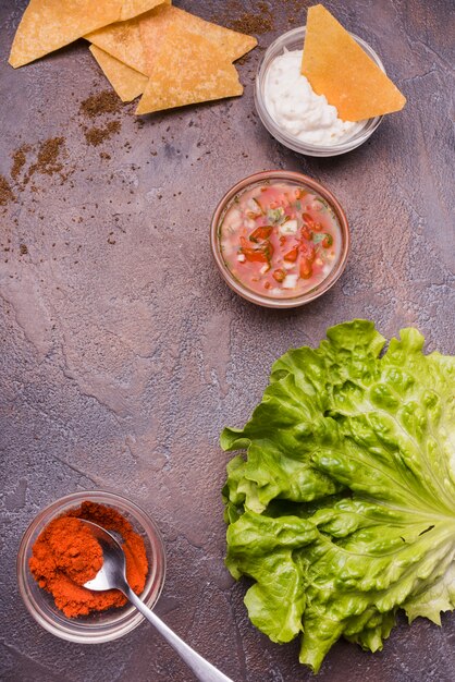 Vegetables among nachos with sauces and chili