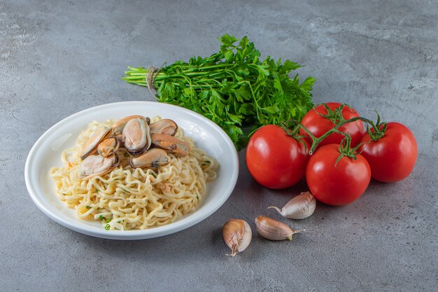 大理石の表面の皿の上の麺の隣の野菜。