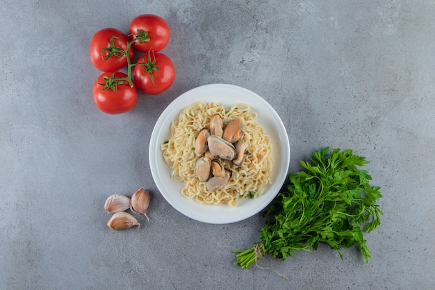 Foto gratuita verdure accanto alla tagliatella su un piatto, sulla superficie di marmo.