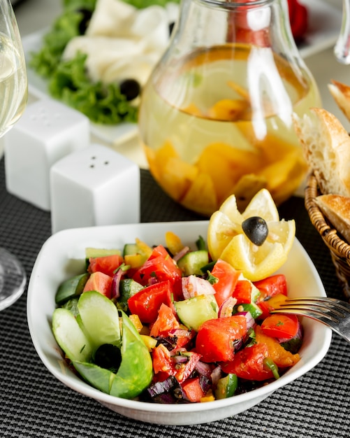 Free photo vegetables salad in a bowl woth lemon and black olives.