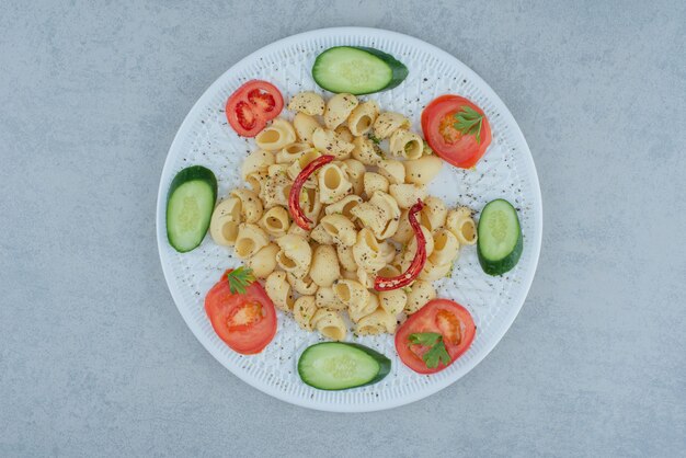 대리석 배경에 맛있는 마카로니와 흰 접시에 야채 샐러드