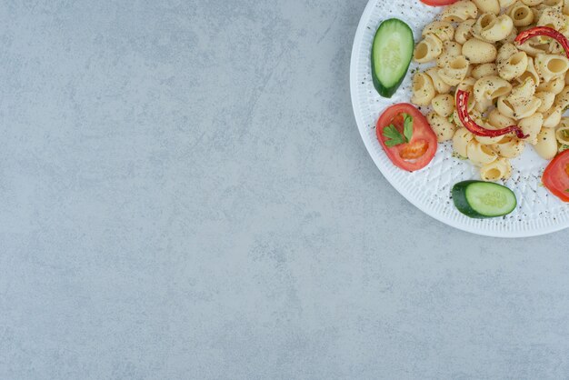 대리석 배경에 맛있는 마카로니와 흰 접시에 야채 샐러드