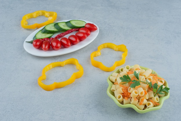 Vegetables salad on white plate with macaroni on marble background. high quality photo