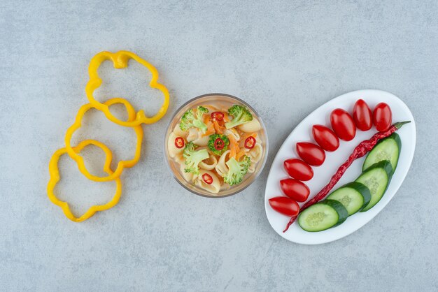 Vegetables salad on white plate with macaroni on marble background. High quality photo